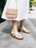 Foto de estilo de vida de una modelo usando las sandalias Itaca en color dorado, destacando un look brillante, relajado y con mucho estilo para el día a día.
