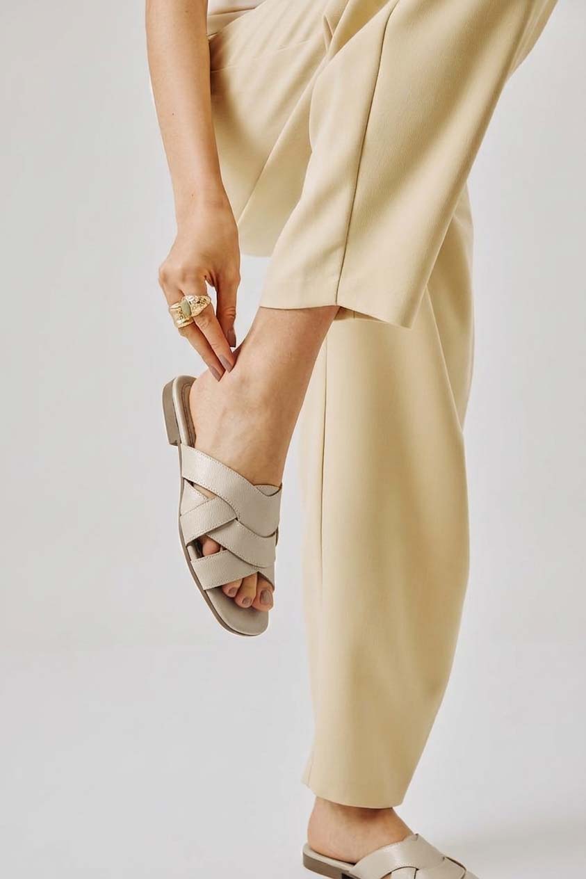 Modelo luciendo las sandalias Nacar en color beige en un ambiente interior, evocando una sensación de comodidad, frescura y elegancia natural.
